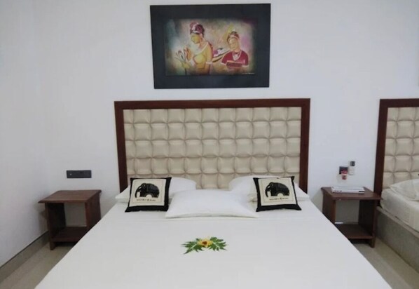 A hotel room with a large bed, two nightstands, a framed picture above the bed, and a small table with a lamp.