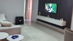 A living room with a flat-screen TV mounted on the wall, a sofa, a coffee table, and a small side table.