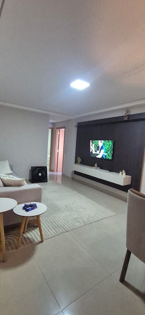 A living room with a flat-screen TV mounted on the wall, a sofa, a coffee table, and a small side table.