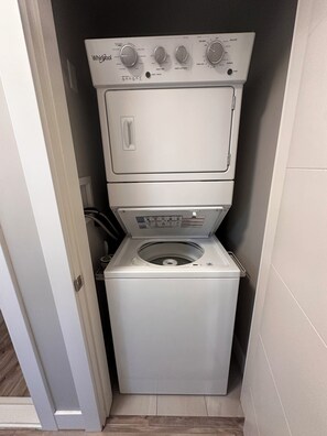 A compact, white Whirlpool washer and dryer unit in a small laundry room with a tiled floor.