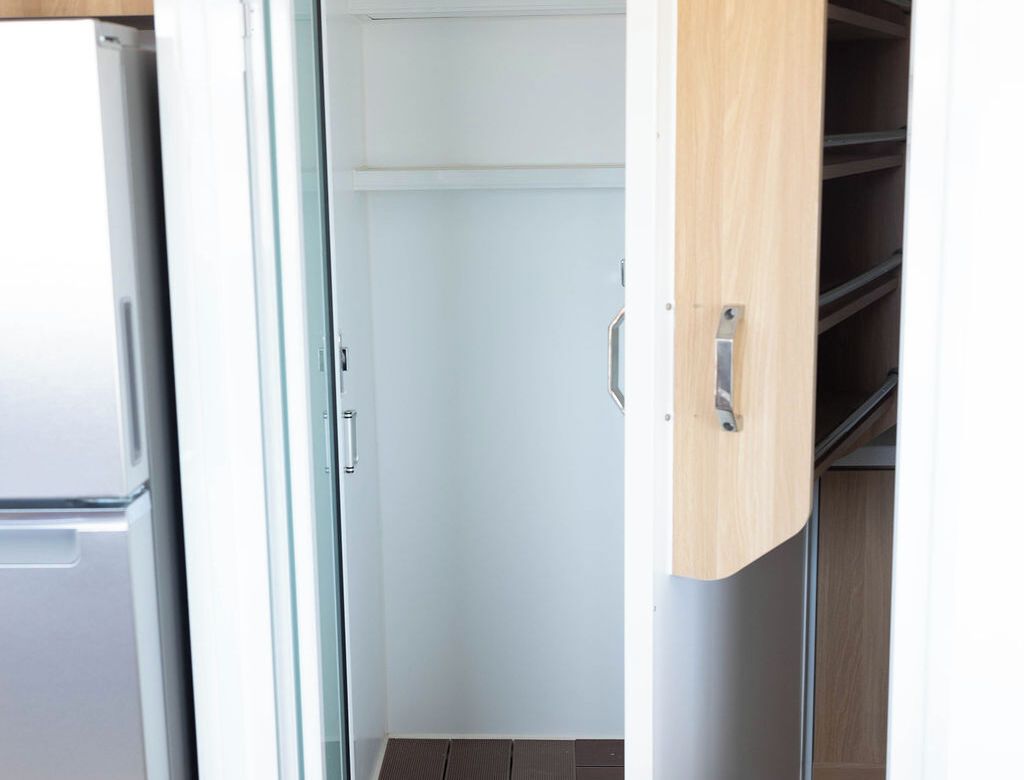 A kitchen with a refrigerator, a wooden cabinet, and a white door.
