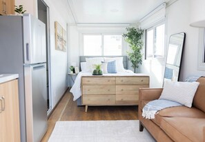 A bedroom with a bed, dresser, and a mirror. - BoxHouse Villages Monahans: Compact Queen Suite (Monahans)
