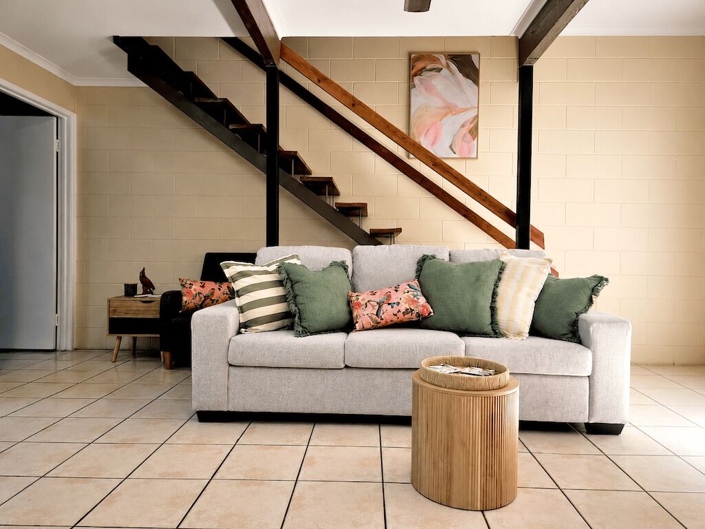 A living room with a sofa, a coffee table, and a staircase.