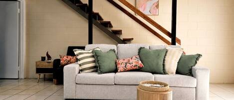 A living room with a sofa, a coffee table, and a staircase.
