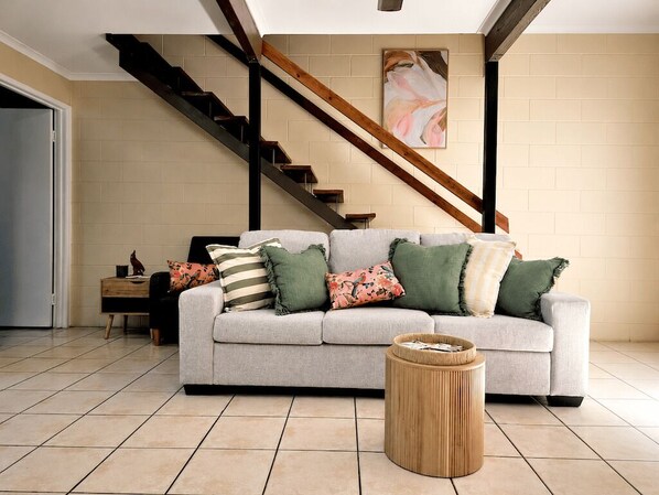 A living room with a sofa, a coffee table, and a staircase.