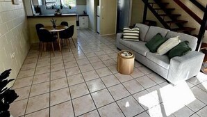 Ein geräumiger Wohnbereich mit Esstisch, Sofa und Treppe zu einer oberen Etage.