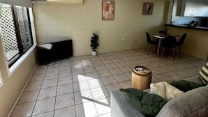 Ein Wohnzimmer mit einer Couch, einem Esstisch und einem Deckenventilator.