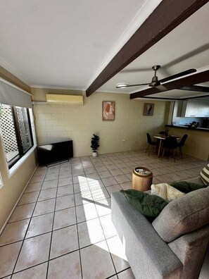 A living room with a sofa, a dining table, and a ceiling fan.