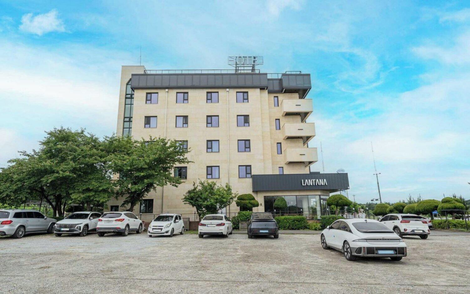 A multi-story hotel building with a sign reading 'LANTANA' and a parking lot with several cars.