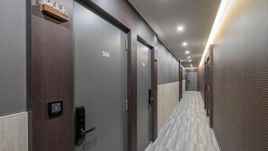 Pasillo de hotel con puertas numeradas 506 y 507, un panel de control y una alfombra estampada.