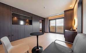 Ein modernes Hotelzimmer mit großem Fenster, einem runden Tisch und einer Sitzecke.