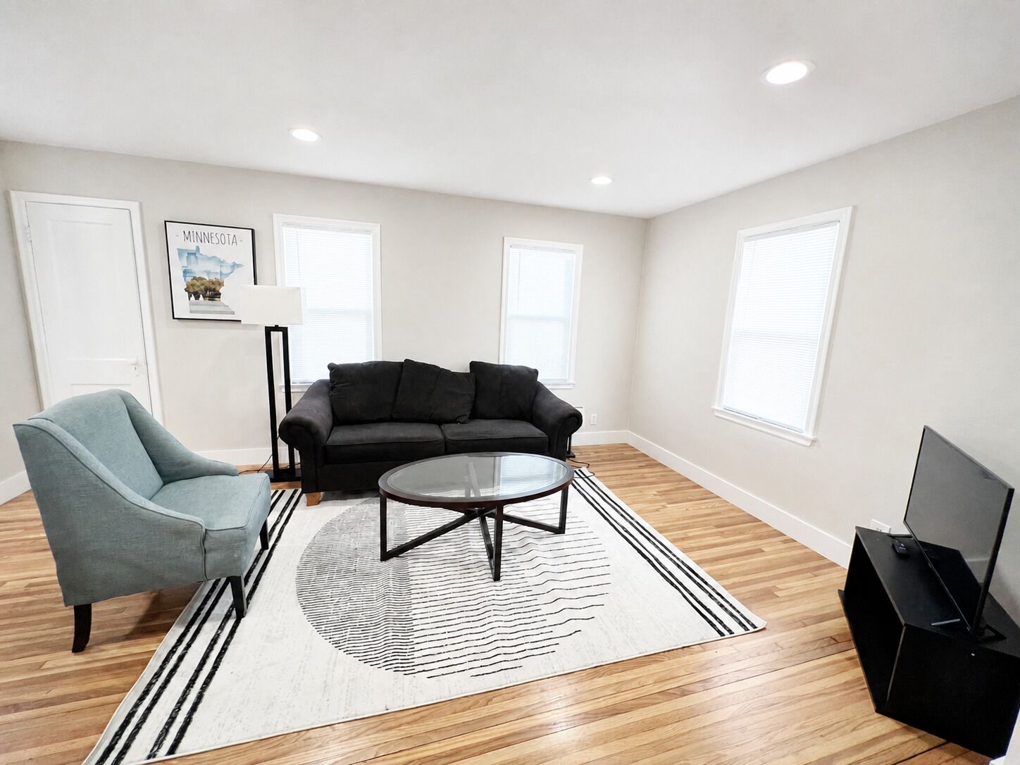 A living room with a sofa, armchair, coffee table, and a flat-screen TV.