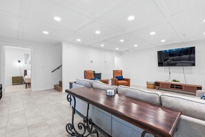Een moderne woonkamer met een flatscreen televisie, een houten salontafel en een grijze bank.