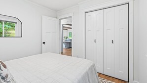 A bedroom with a bed, a wardrobe, and a door leading to a living area.