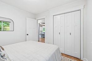 A bedroom with a bed, a wardrobe, and a door leading to a living area.
