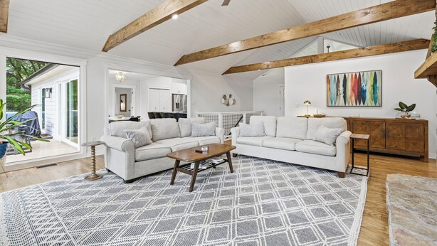 A spacious living room with a white sofa set, a coffee table, and a patterned rug.