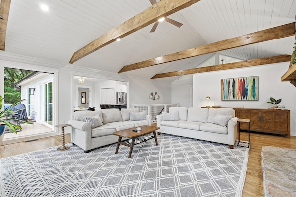 A spacious living room with a white sofa set, a coffee table, and a patterned rug.