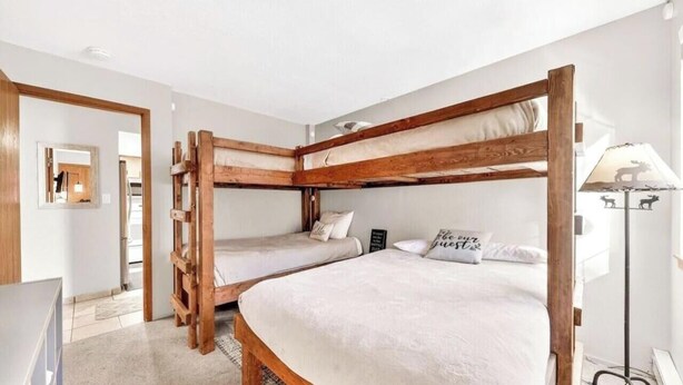 Quarto com beliche de madeira, mesa de cabeceira e luminária.