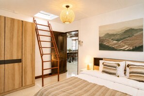 A bedroom with a bed, a wooden wardrobe, a ladder, a hanging light fixture, a painting, and a door leading to a dining area. - 4-Bedroom House in Chang Khlan Chiang Mai (Chang Wat Chiang Mai)