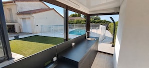 A modern kitchen with a view of a backyard swimming pool. - Large, air-conditioned villa with a private, secure pool and no overlooking neighbors - Servian (Servian)