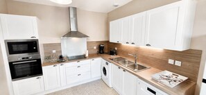 A modern kitchen with built-in appliances, a stainless steel range hood, and a wooden backsplash. - Large, air-conditioned villa with a private, secure pool and no overlooking neighbors - Servian (Servian)