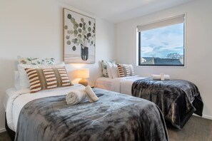 Una camera d'albergo con due letti, una finestra vista e un quadro appeso al muro.