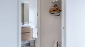 A hallway leading to a bathroom with a white radiator and a hanging clothes rack.