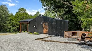 A small, dark wooden building with a wooden door and a small porch.