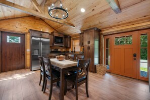 A wooden interior with a kitchen, dining table, chairs, and a refrigerator.