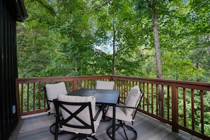 A wooden deck with a table and chairs, surrounded by trees. - Copperwood Run (Clarkson)