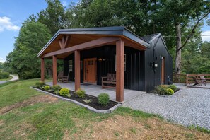 Eine Hütte mit Veranda, einer Holztür und einem kleinen Garten.