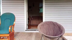 Una terraza de madera con una mecedora y un sillón colgante.