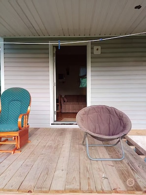 Eine Holzterrasse mit einem Schaukelstuhl und einer Hängematte.
