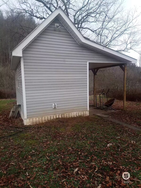 A small, single-story shed with a sloped roof and a covered porch area.
