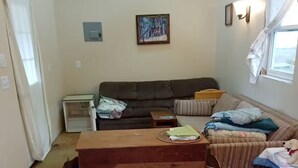 Una habitación amoblada con cama, sofá, una mesita y ventana.