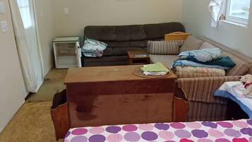 Una habitación amoblada con cama, sofá, una mesita y ventana.
