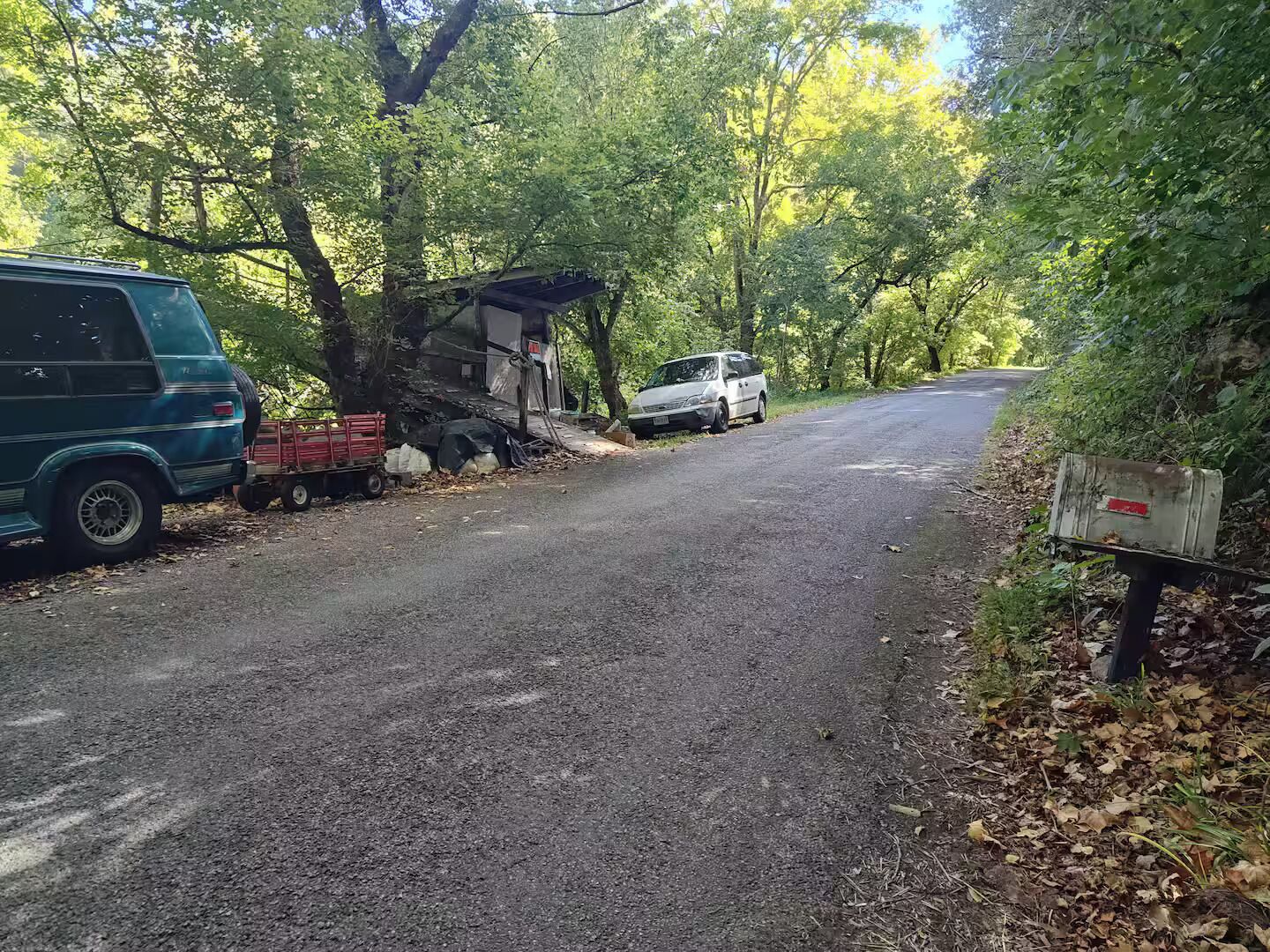 Una strada sterrata con un furgone e un'auto bianca parcheggiati a lato.