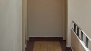 Un corridoio con una lampada a soffitto, una porta in fondo e un pavimento piastrellato.
