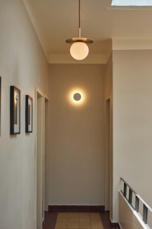 En gang med en loftslampe, en dør i enden og et flisegulv.