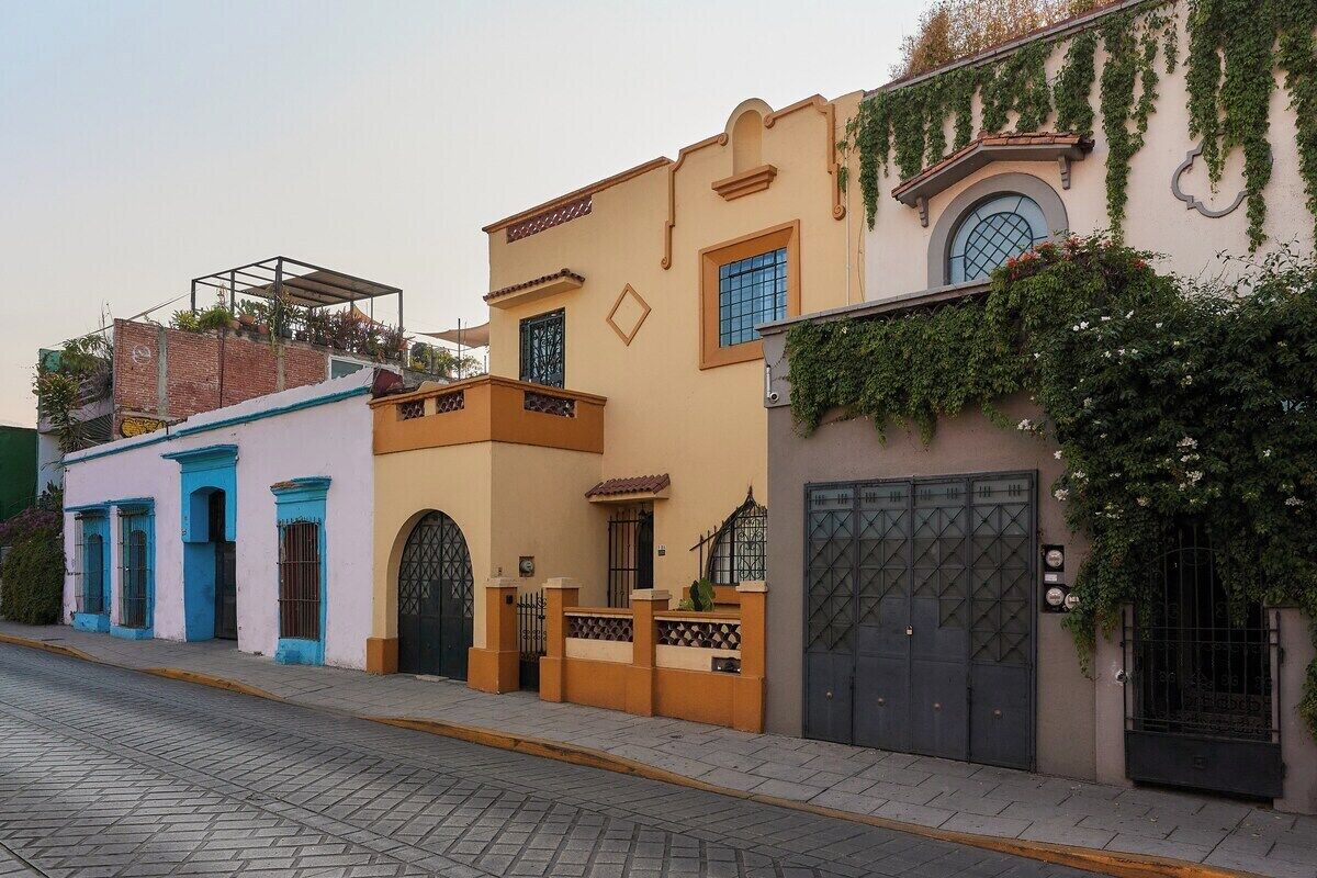 A row of buildings with distinct architectural styles, including a building with a balcony and another with a gate.