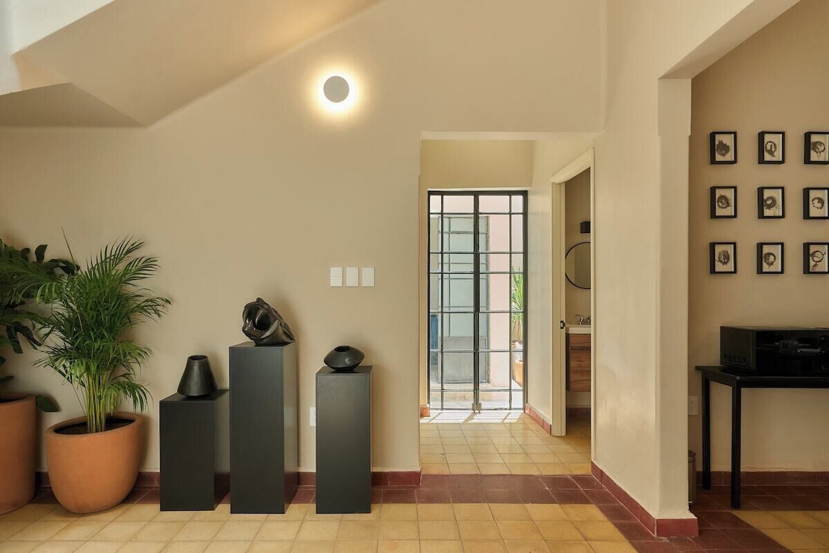 A modern interior with a potted plant, a black sculpture, and a framed picture collection on the wall.