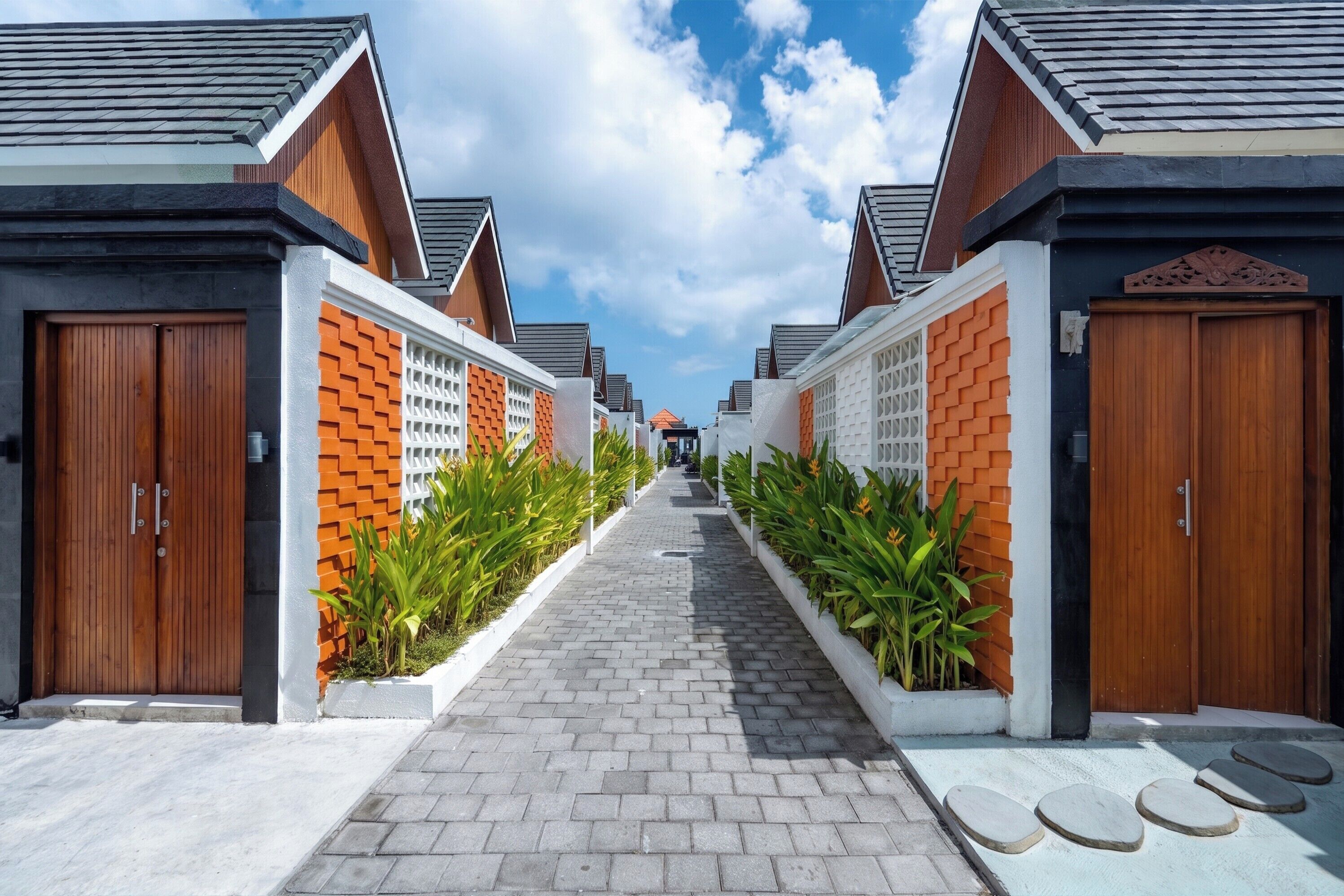 A pathway leading to a row of modern buildings with wooden doors and brick accents.