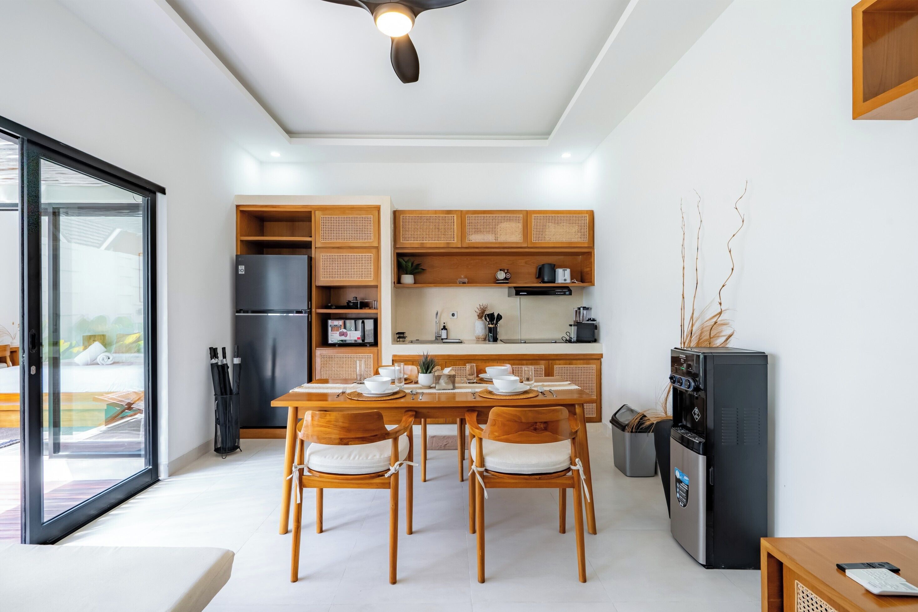 A modern kitchen with wooden cabinets, a dining table with chairs, and a coffee machine.