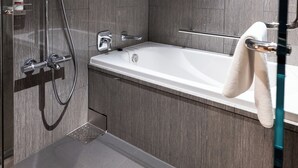 Un baño moderno con ducha a ras de suelo, bañera y cabina de ducha con paredes de vidrio.