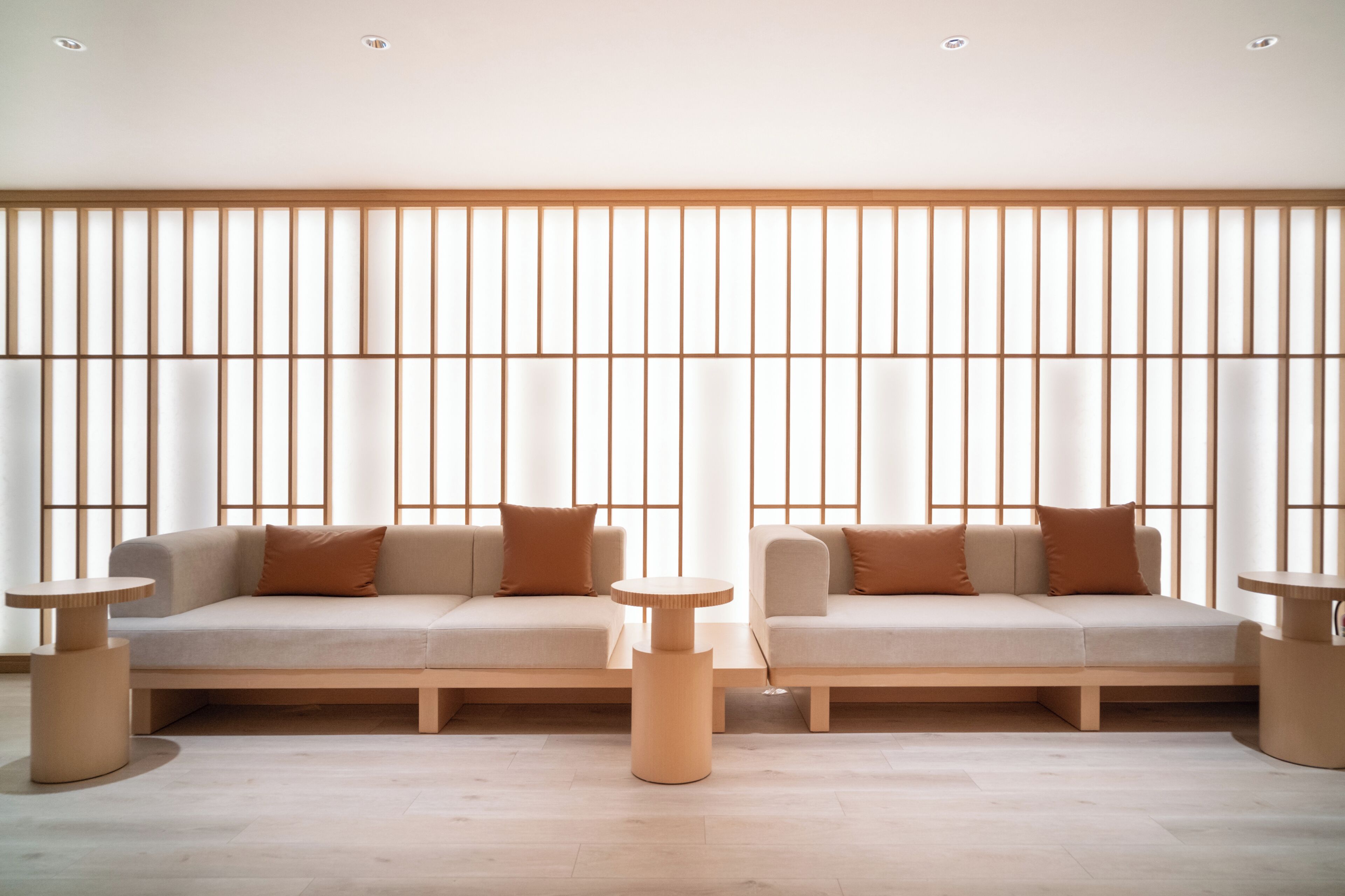 Una sala de estar moderna con un conjunto de sofá, dos mesas auxiliares y piso de madera.