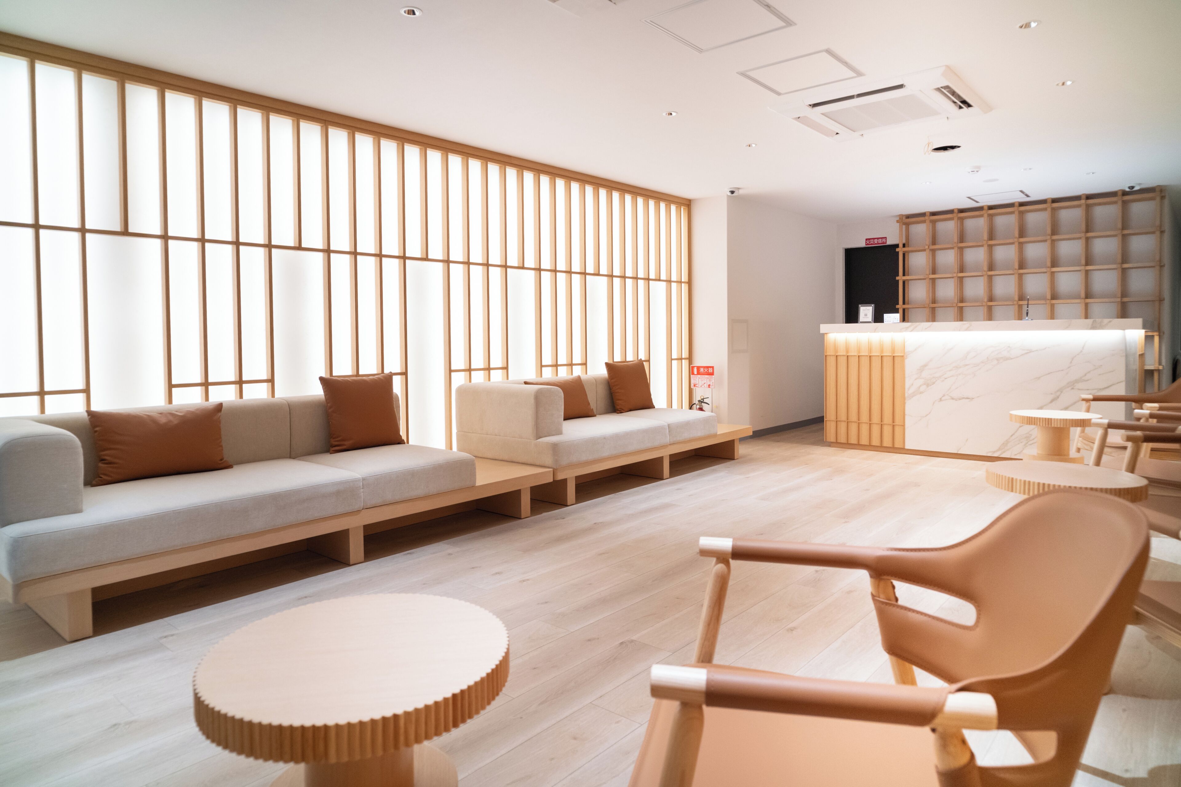 Ein modernes Interieur mit einer Couch, Sesseln, einem Empfangstresen und einer Holzwand.