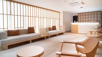 Ein modernes Interieur mit einer Couch, Sesseln, einem Empfangstresen und einer Holzwand.