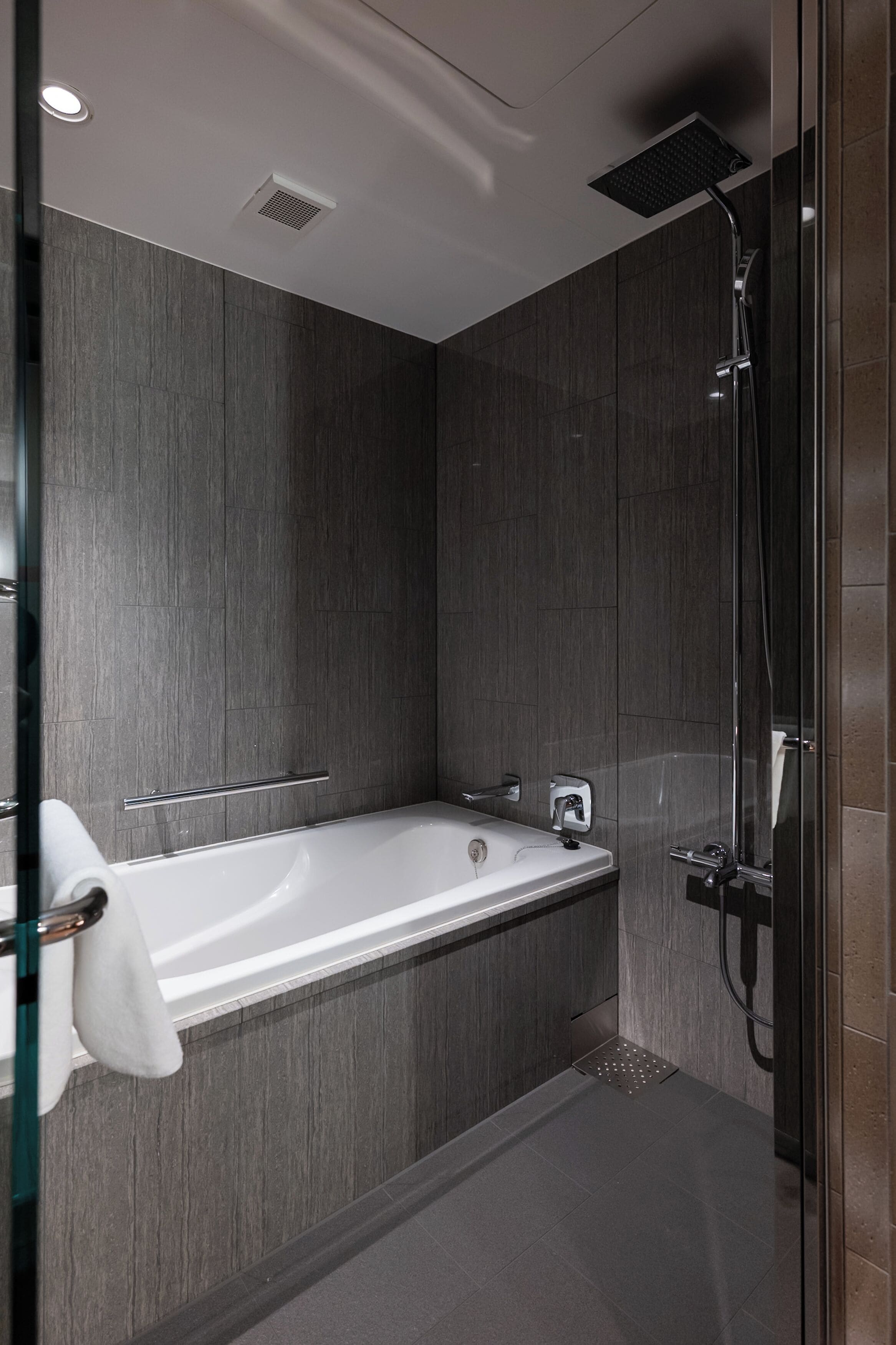 A modern bathroom with a freestanding bathtub, a shower, and a towel rack.