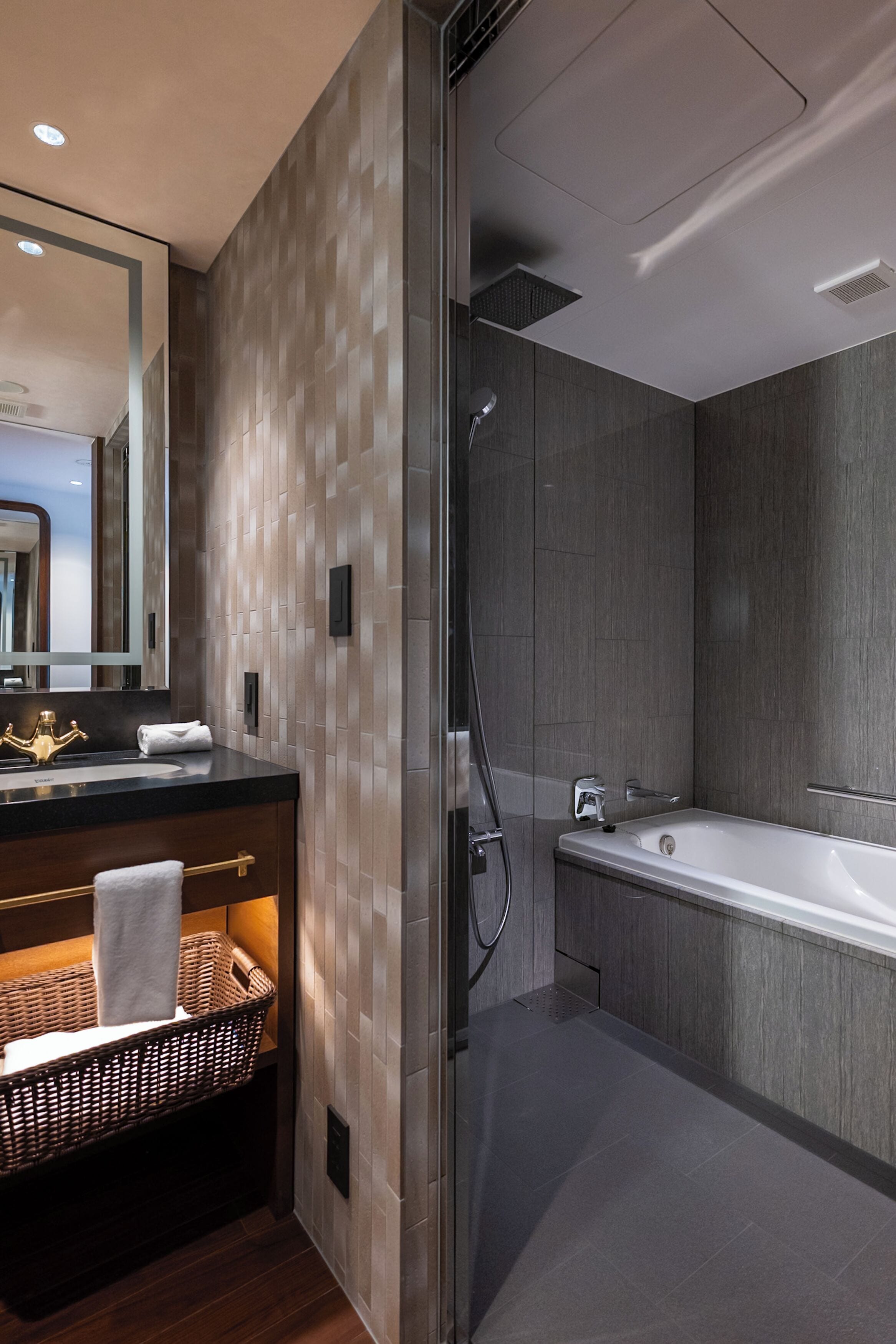 A modern bathroom with a glass-enclosed shower, a large bathtub, and a vanity with a mirror and sink.