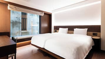 A modern hotel room with a large bed, a desk, and a view of the outdoors.